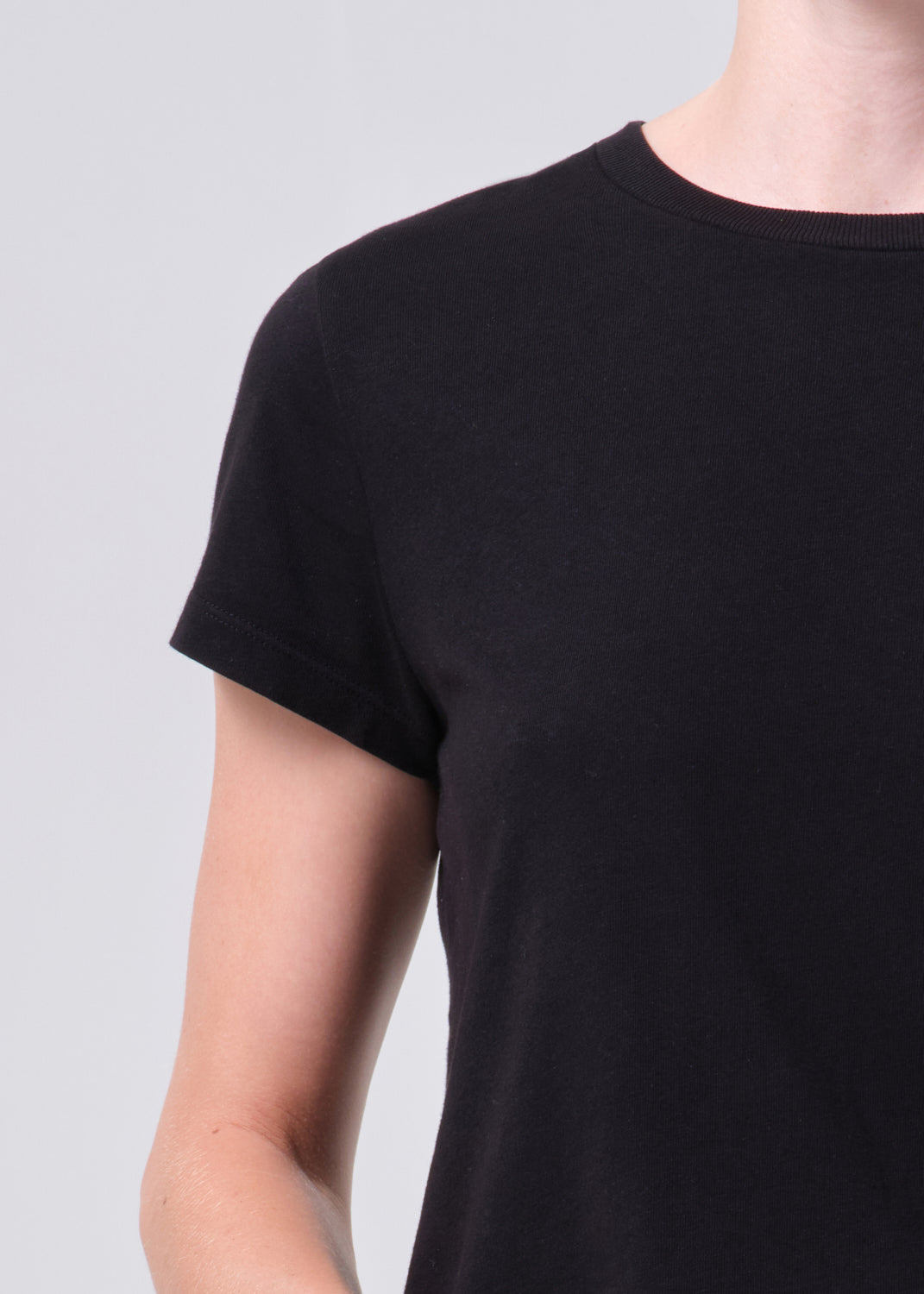 Black t-shirt worn by a person on a light gray background