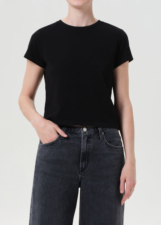Person wearing a black t-shirt and dark jeans on a plain background