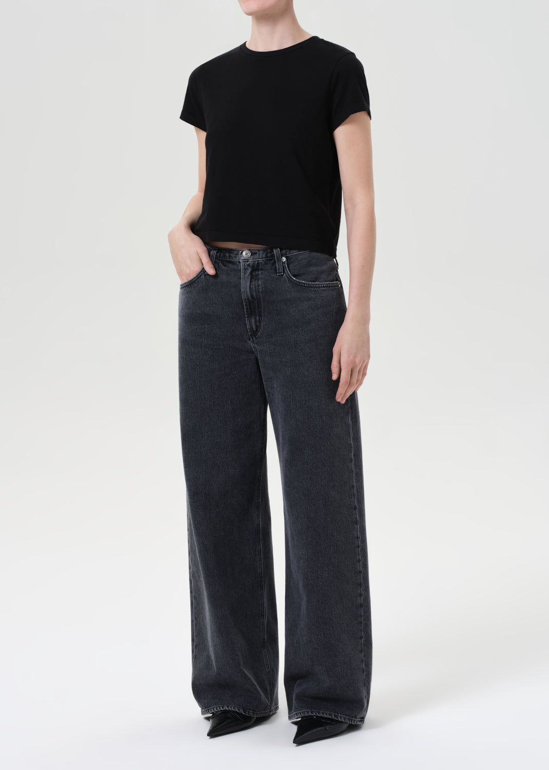 Person wearing black t-shirt and dark jeans on a white background