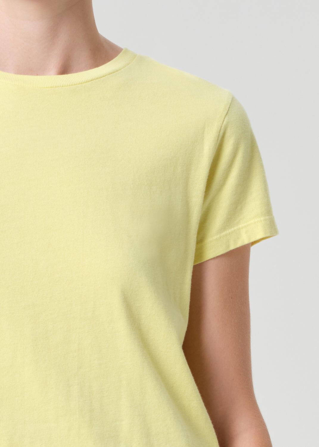 Yellow t-shirt worn by a person on a light gray background