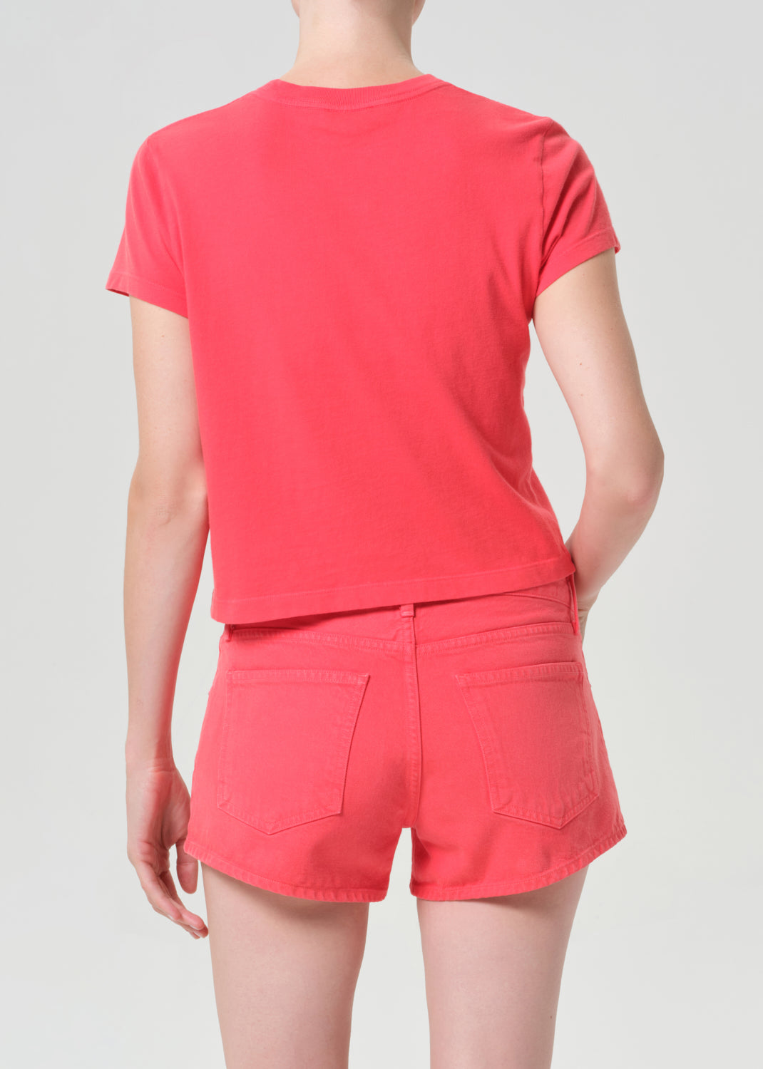 Person wearing a red t-shirt and shorts on a light gray background