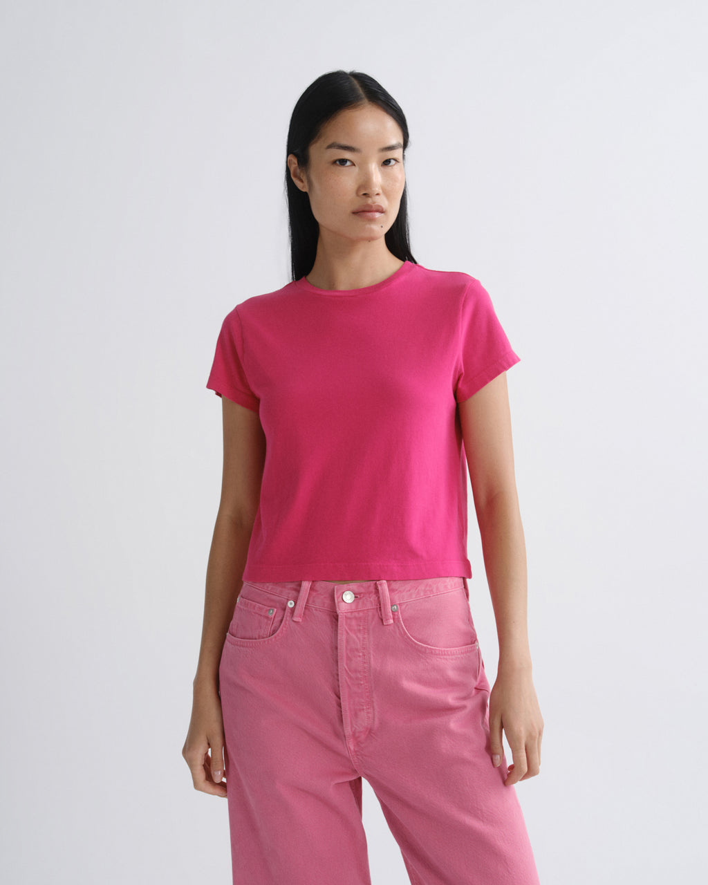 Person wearing a bright pink t-shirt and pants on a white background
