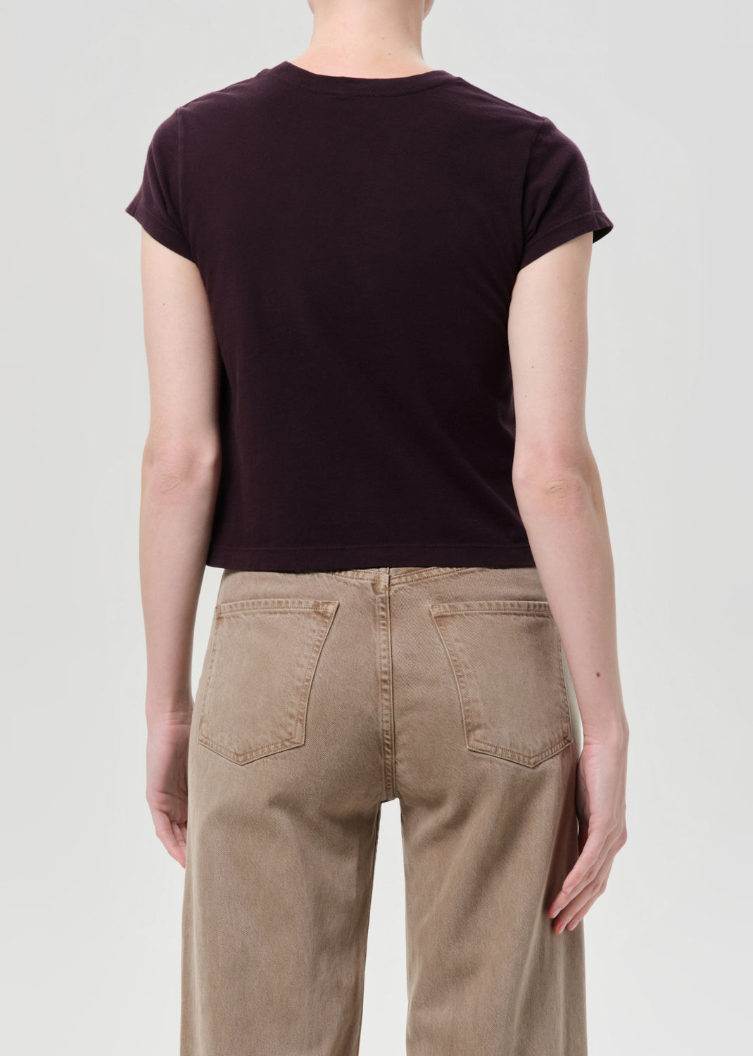Person wearing a black t-shirt and beige pants on a plain background