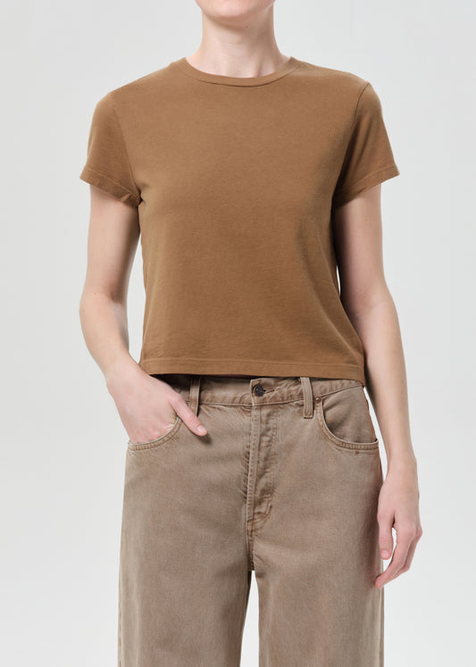Person wearing a brown t-shirt and beige pants on a white background