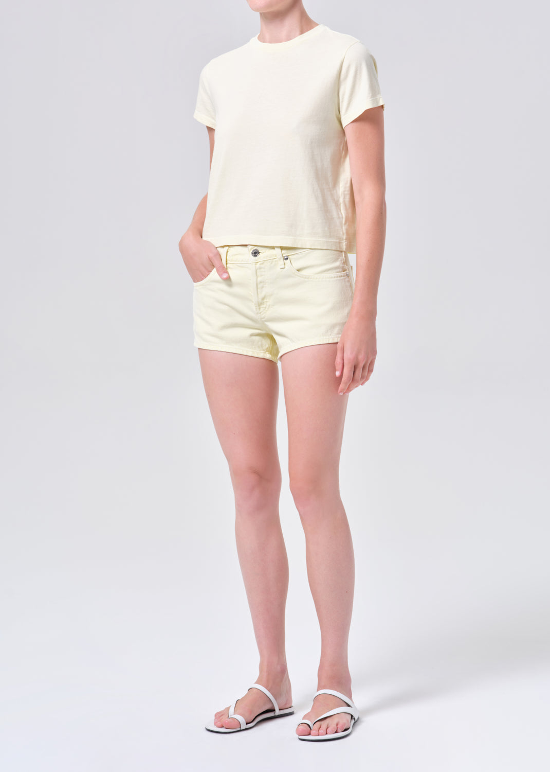 Person wearing a yellow t-shirt and shorts on a white background