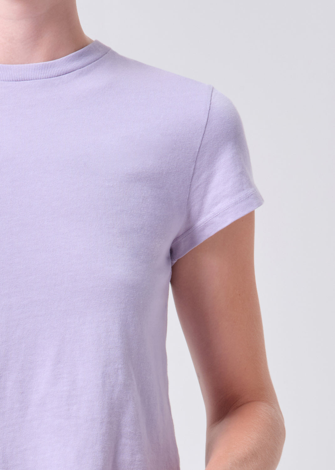 Person wearing a light purple t-shirt against a plain background