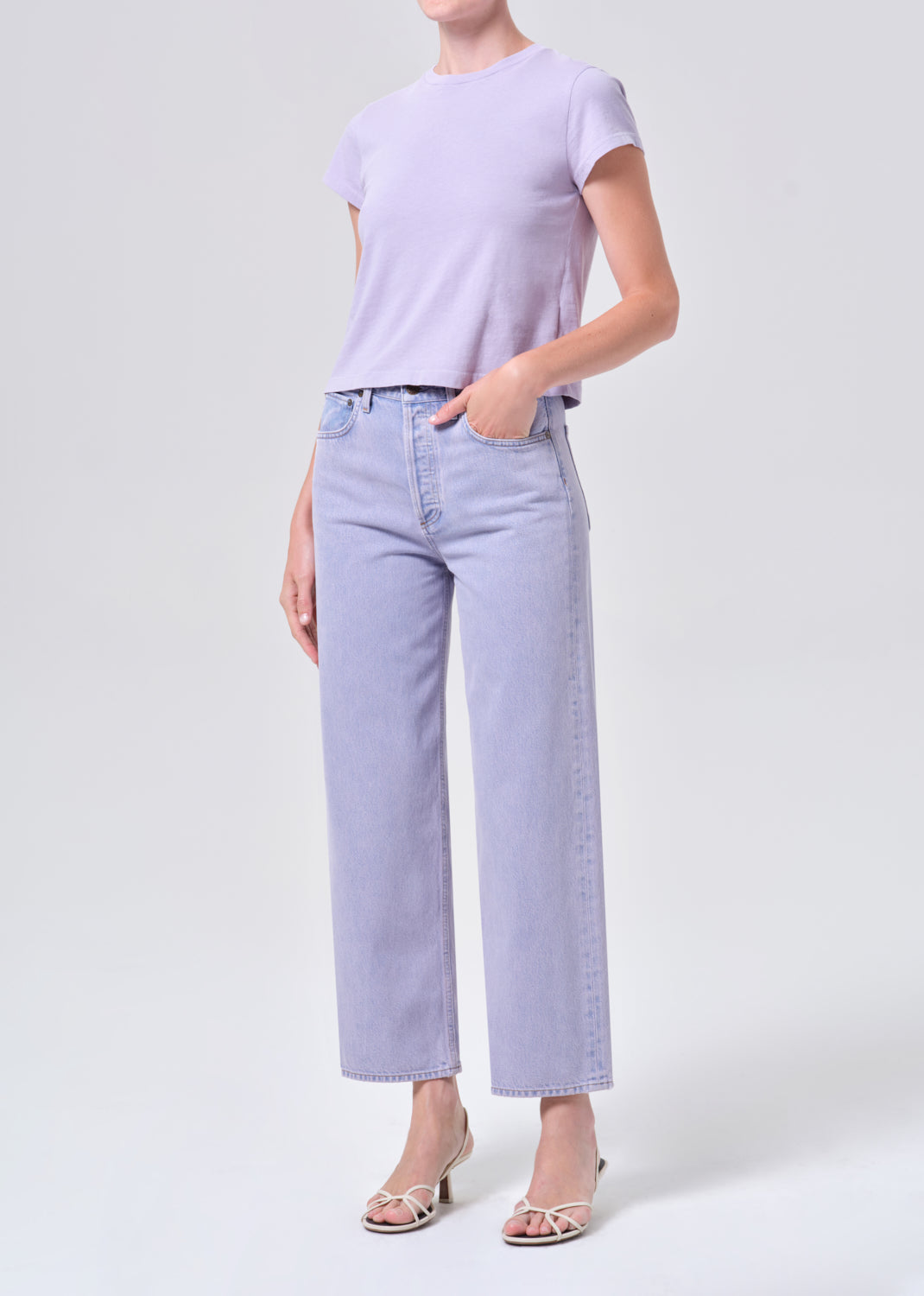 Person wearing a light purple t-shirt and jeans on a white background