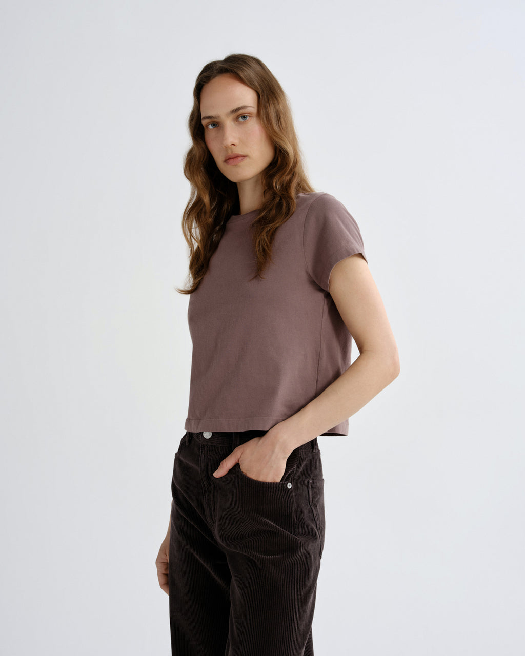 Woman wearing a brown t-shirt and dark pants on a white background