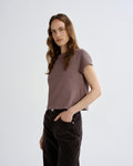 Woman wearing a brown t-shirt and dark pants on a white background
