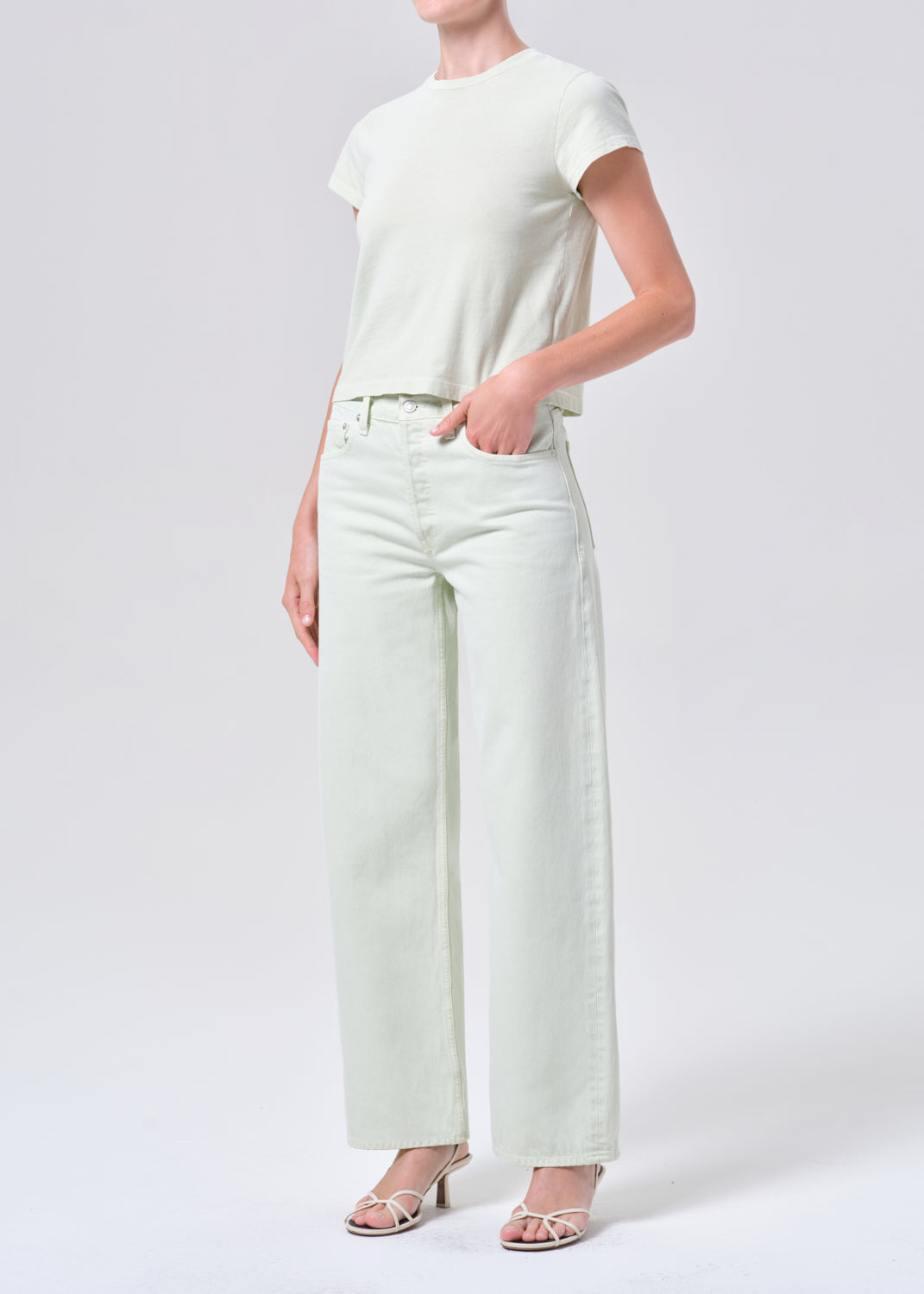 Person wearing a white t-shirt and light green pants on a white background