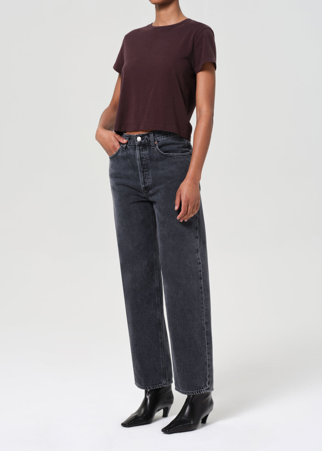 Person wearing a brown t-shirt and black jeans on a white background