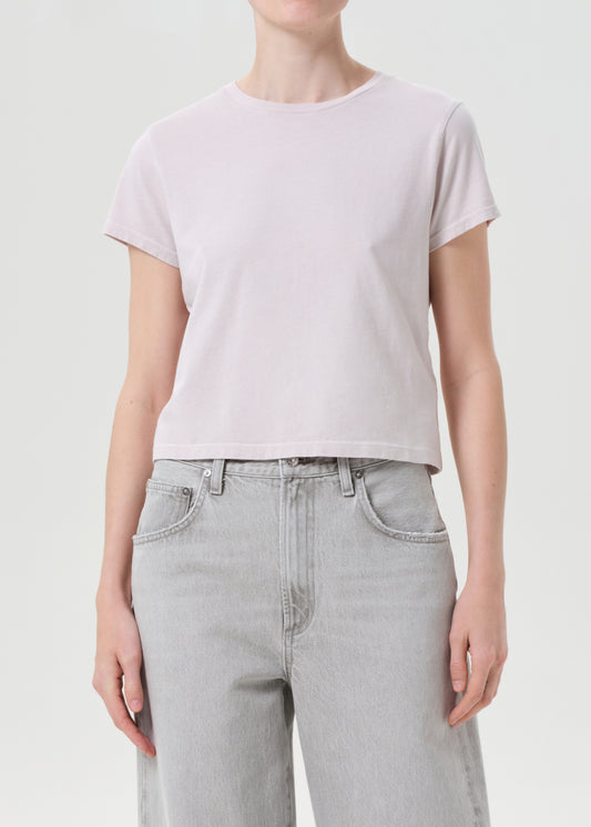 Person wearing a light purple t-shirt and light gray jeans on a plain background