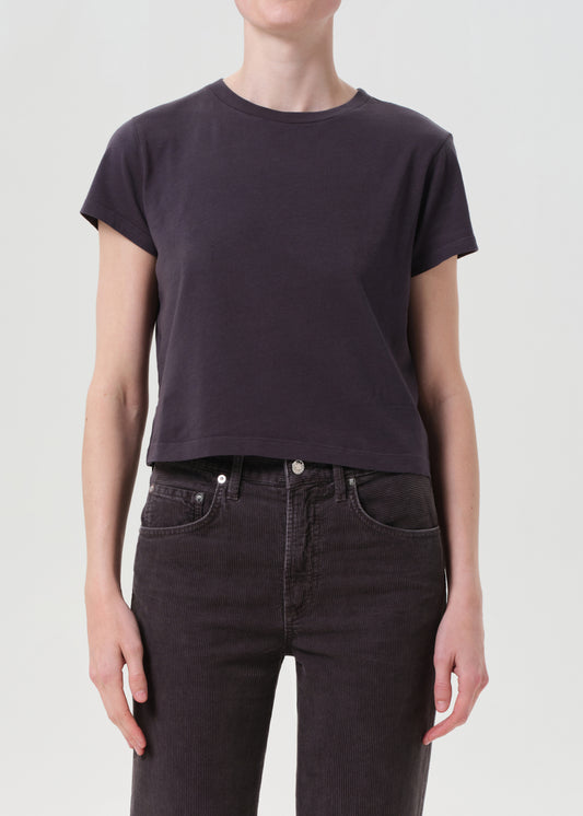 Person wearing a dark purple t-shirt and black jeans on a light gray background