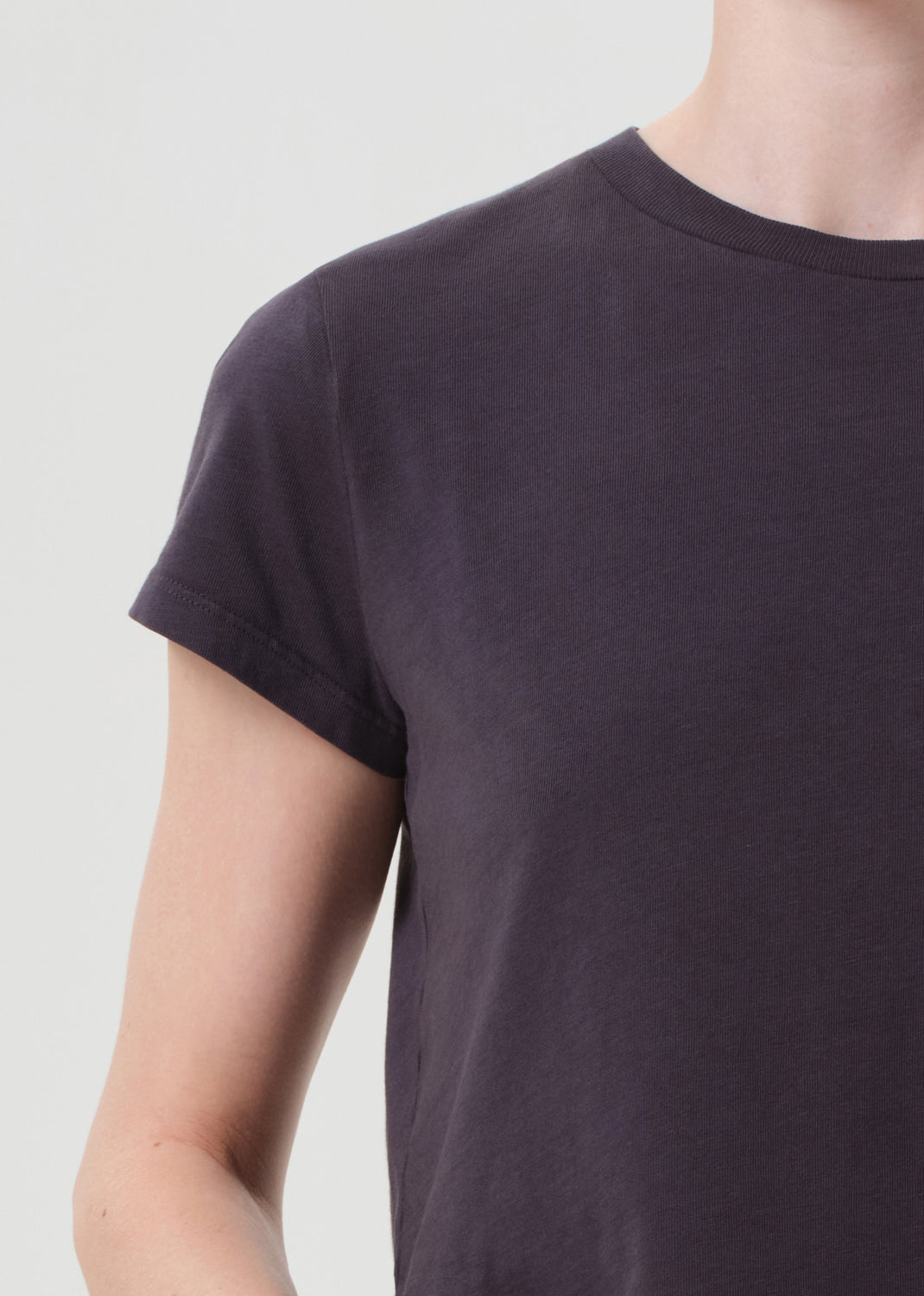 Person wearing a plain dark purple t-shirt against a light gray background