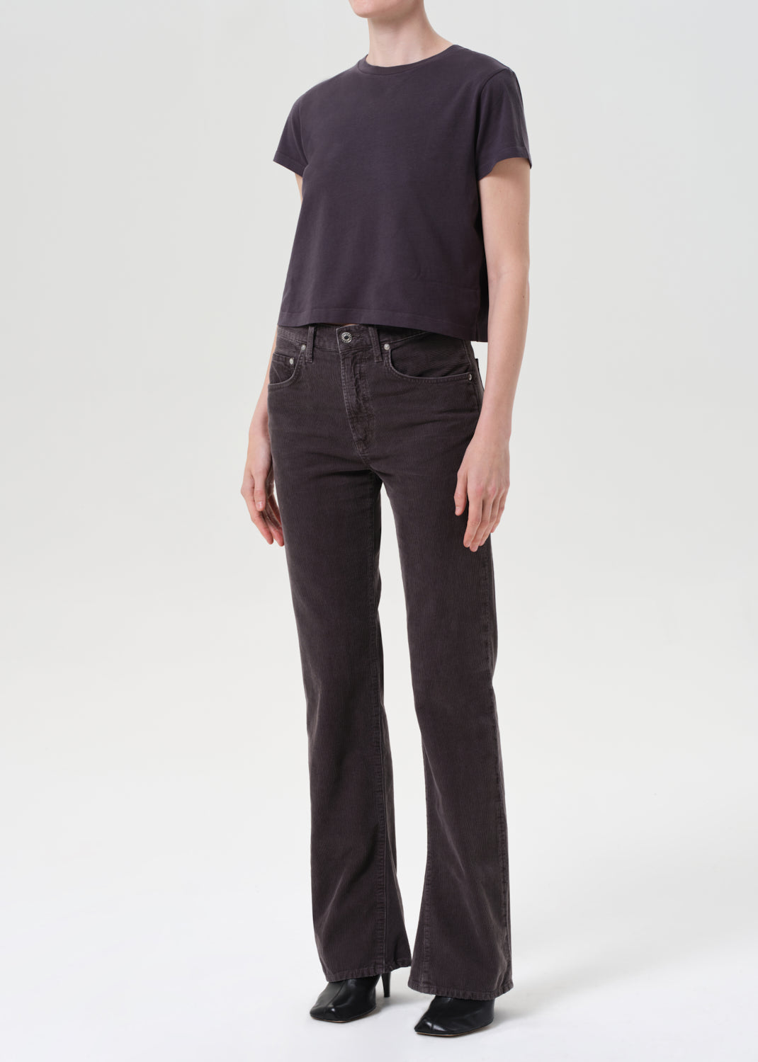 Person wearing a dark purple t-shirt and black jeans on a white background