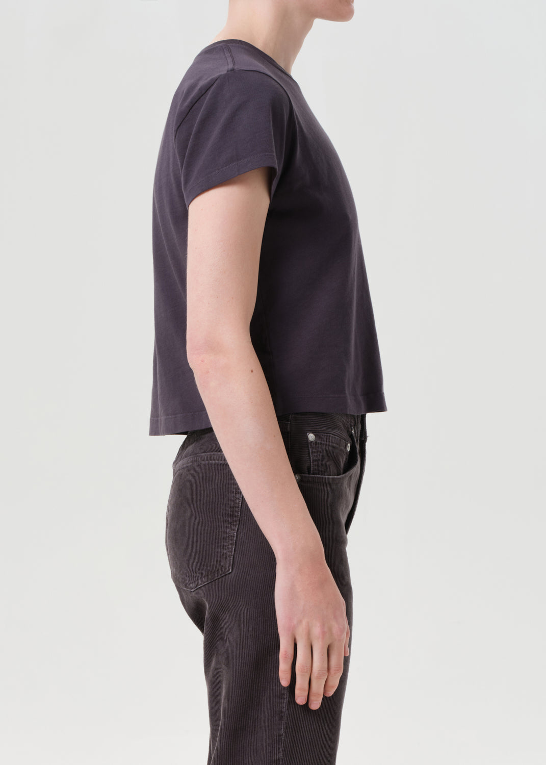 Person wearing a dark purple t-shirt and black pants on a light gray background