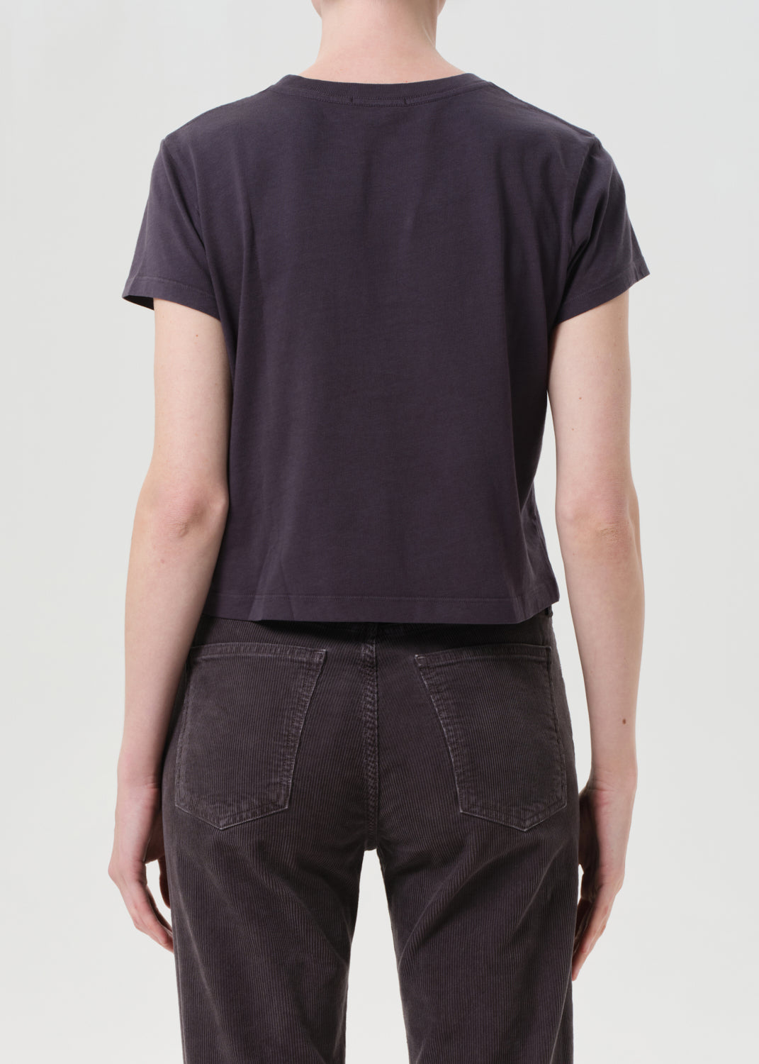 Person wearing a dark purple t-shirt and pants on a light gray background