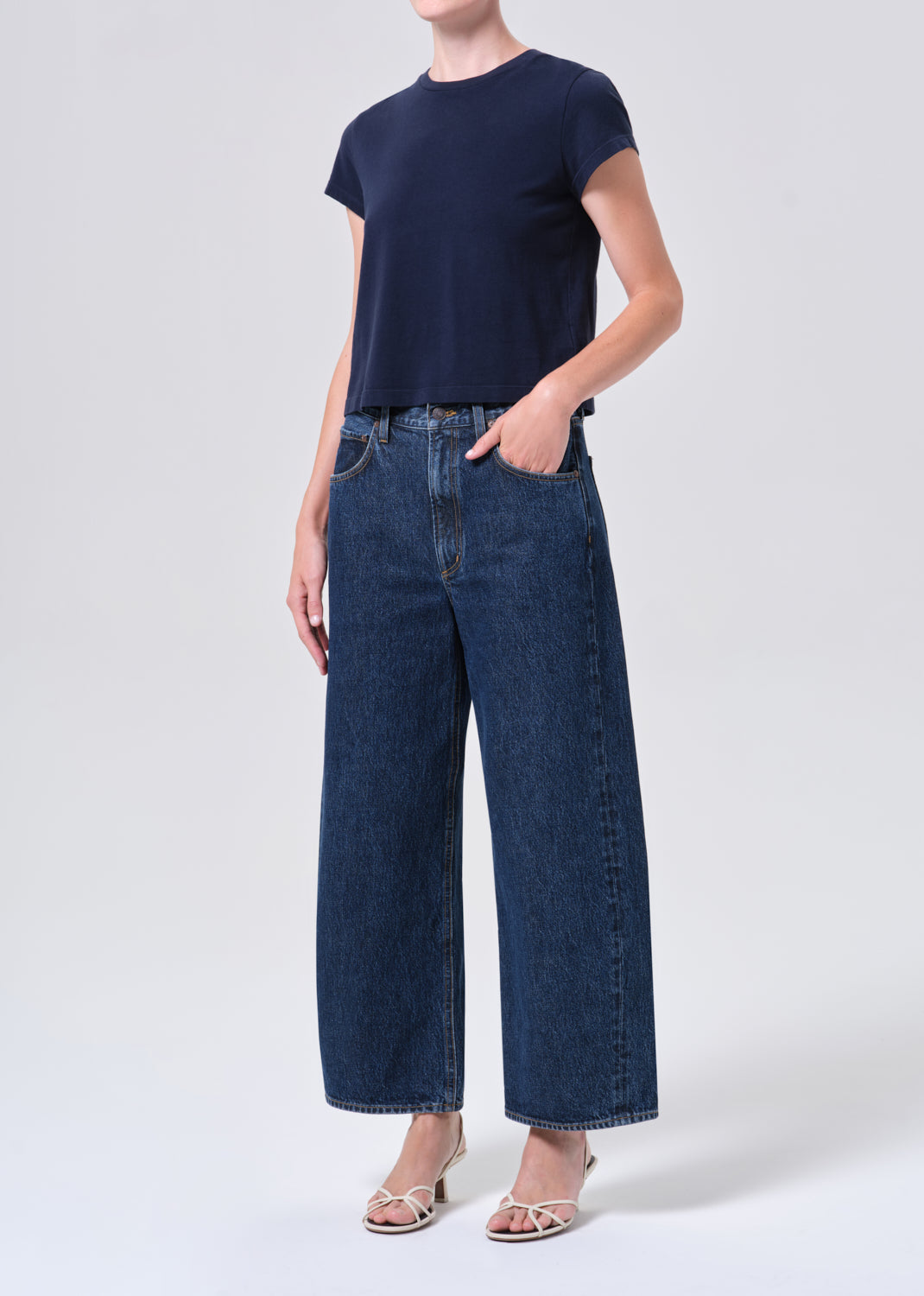 Person wearing a navy t-shirt and blue jeans on a white background