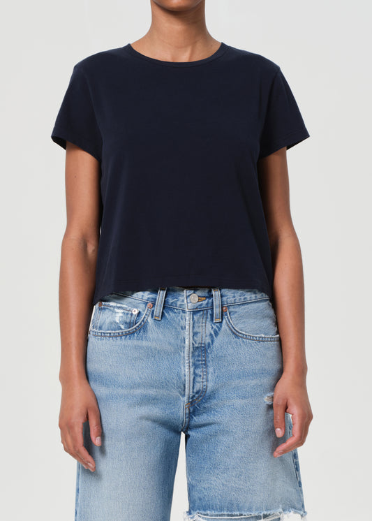 Person wearing a black t-shirt and light blue jeans on a white background