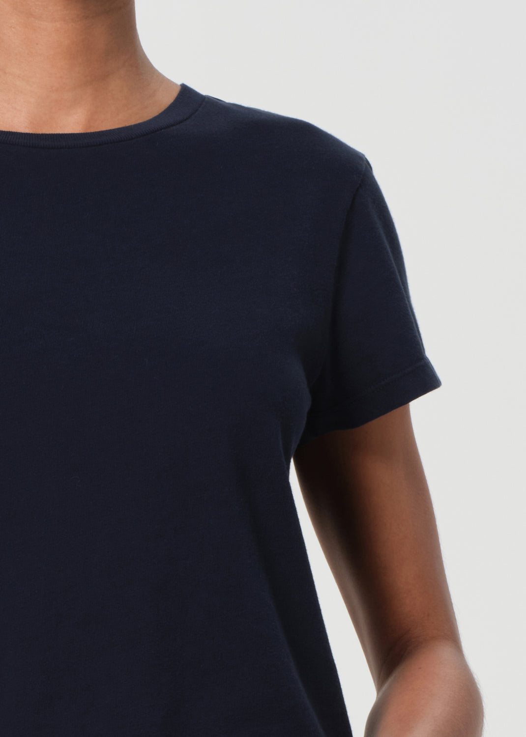 Navy blue t-shirt worn by a person on a white background