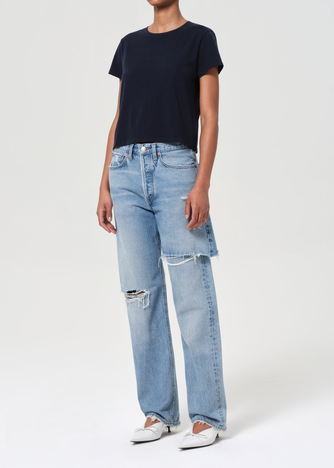 Person wearing a black t-shirt and light blue jeans with a white background