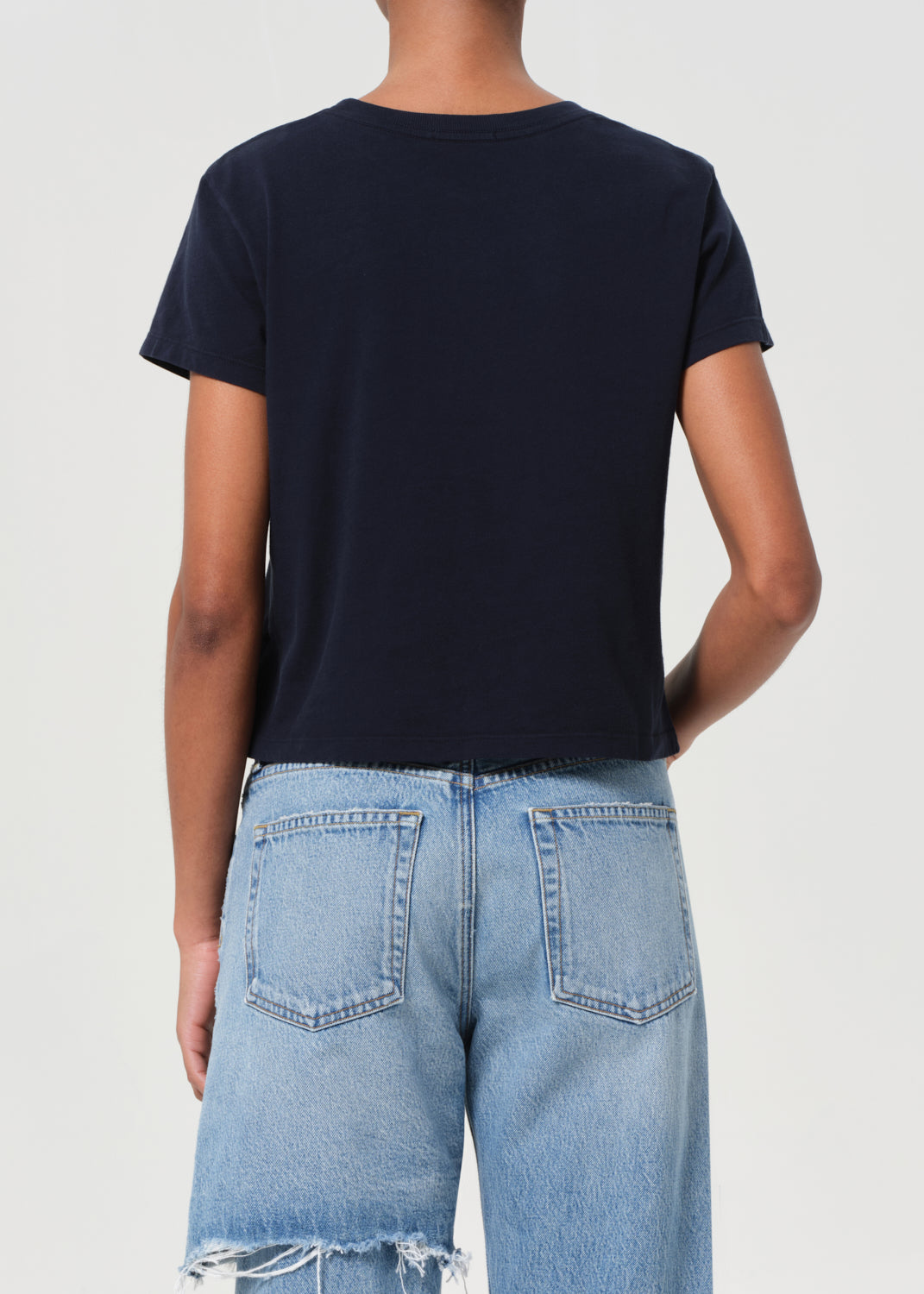 Person wearing a black t-shirt and light blue jeans on a white background