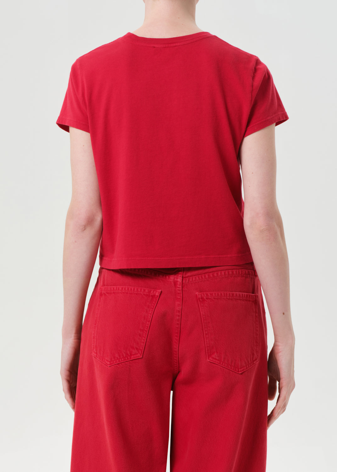 Person wearing a red t-shirt and pants on a plain background