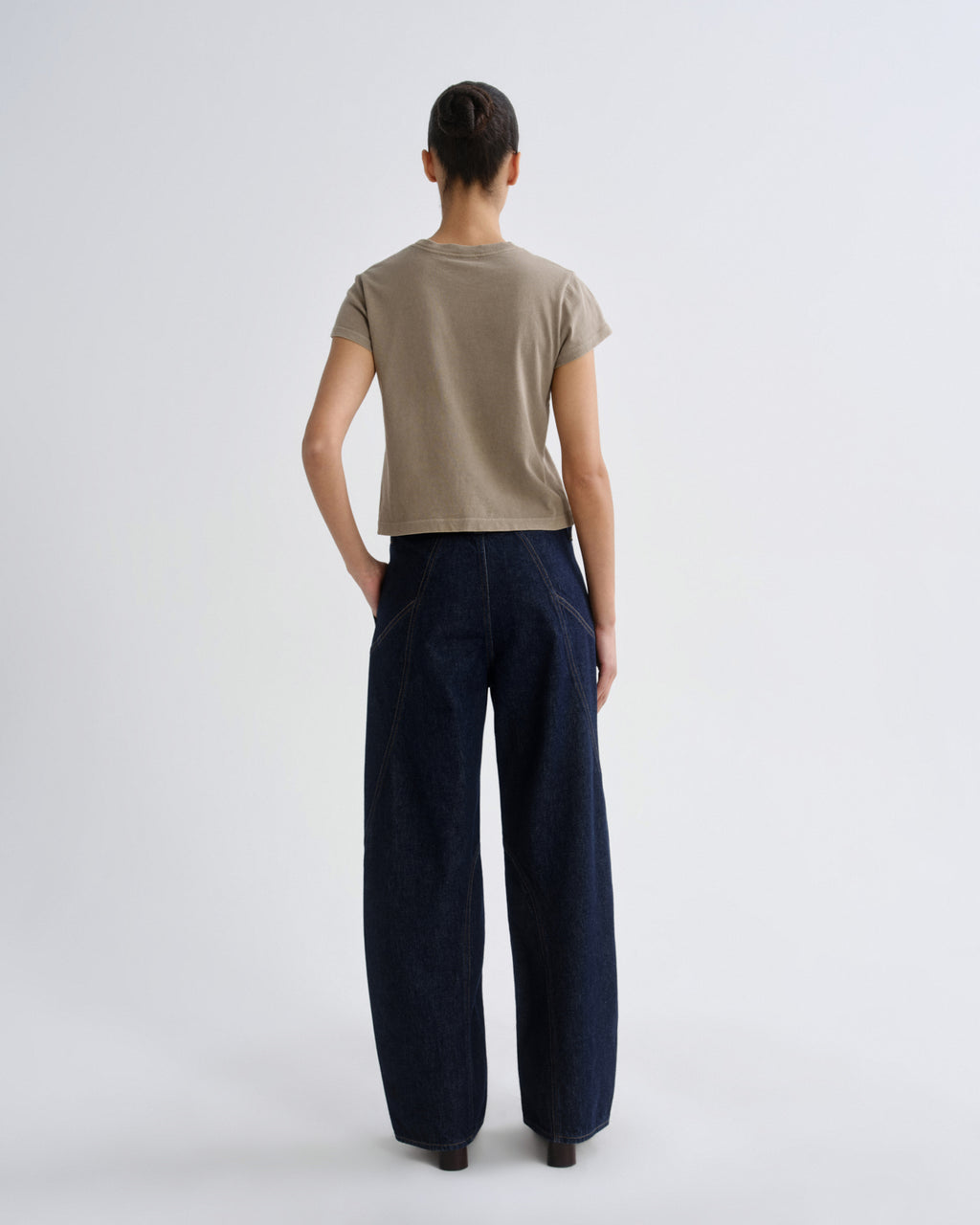 Person wearing a beige shirt and dark blue pants on a white background