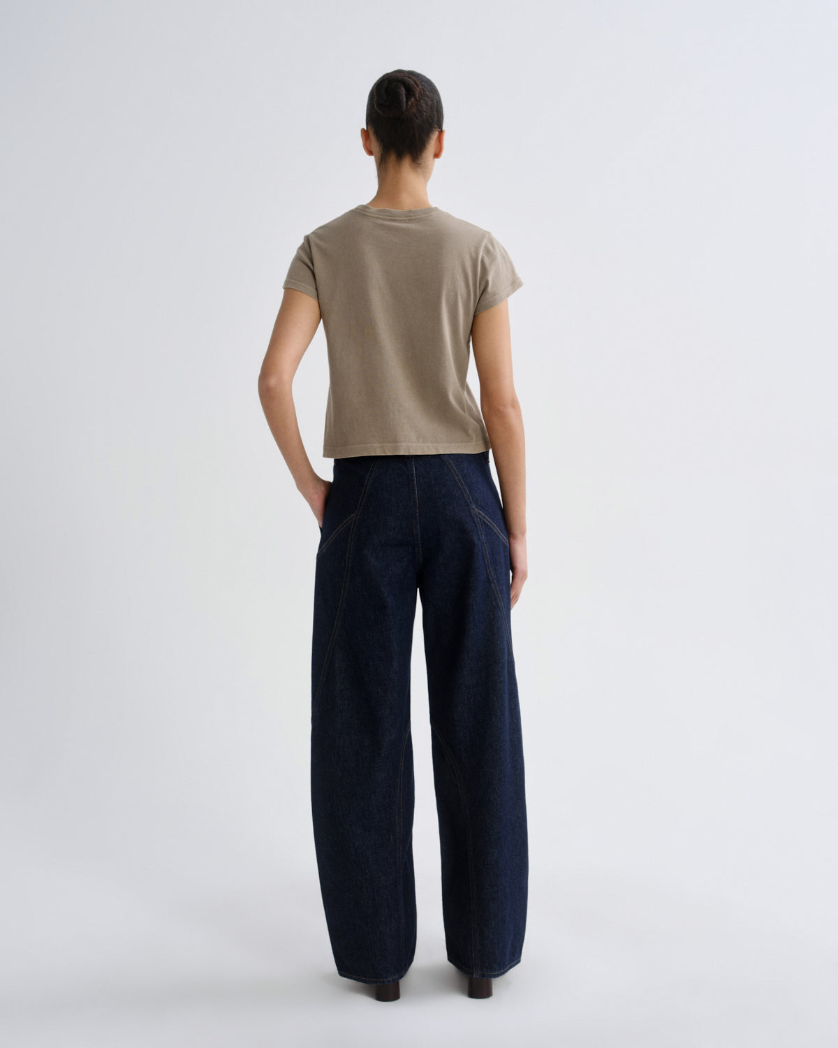Person wearing a beige shirt and dark blue pants on a white background