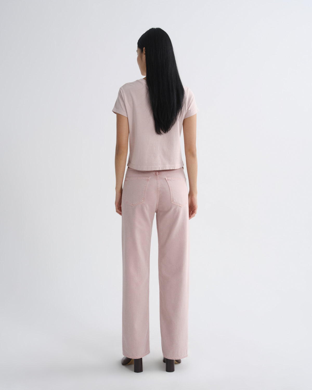Person wearing a light pink outfit on a white background