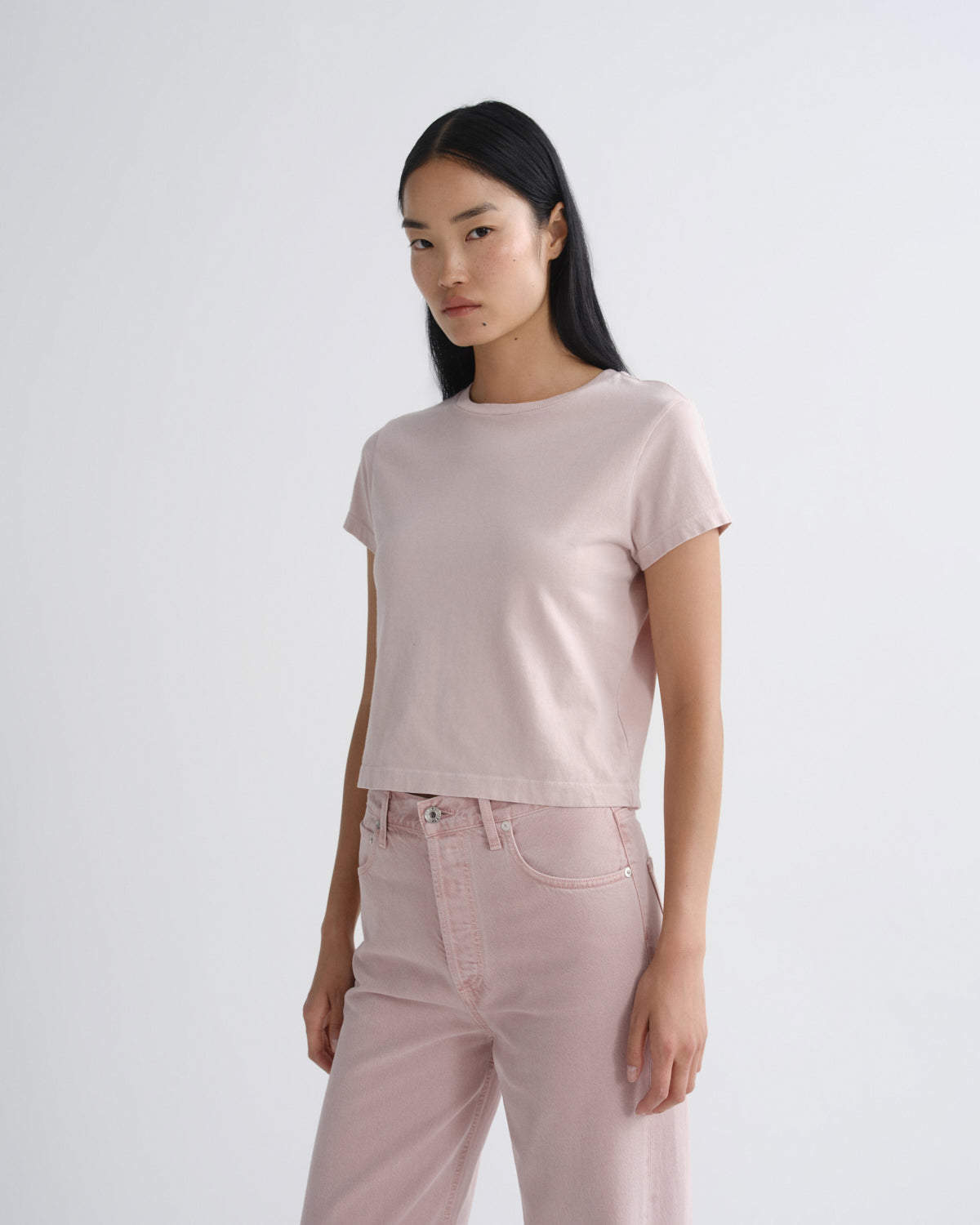 Woman wearing a light pink t-shirt and pants on a white background