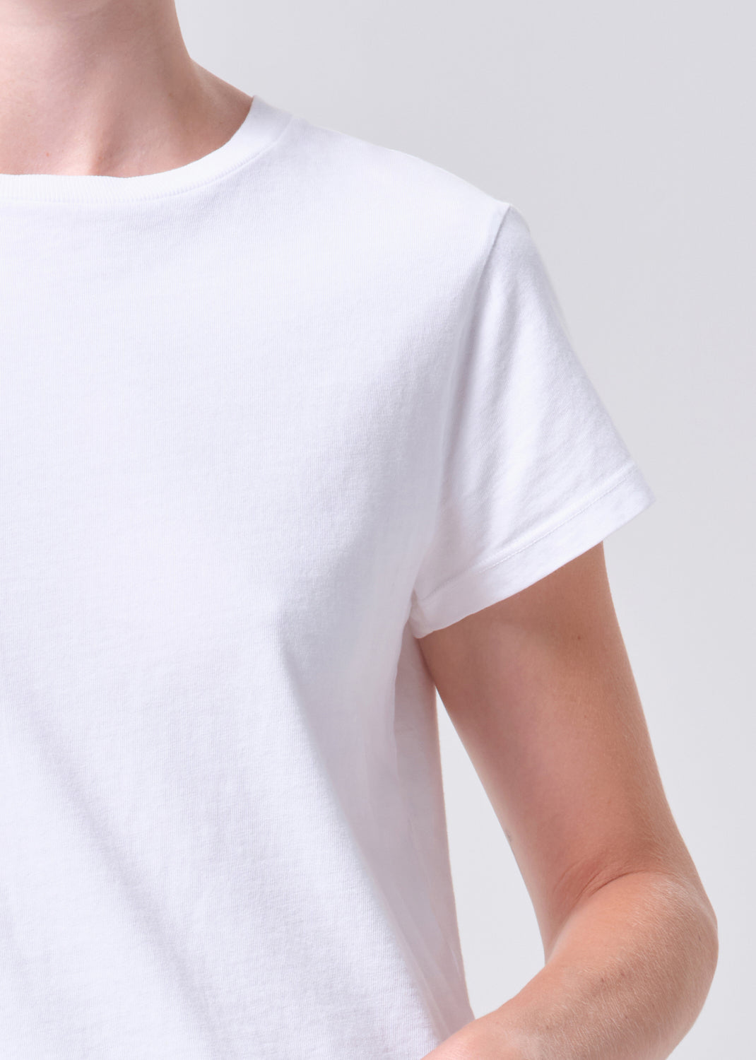 White t-shirt worn by a person on a light gray background