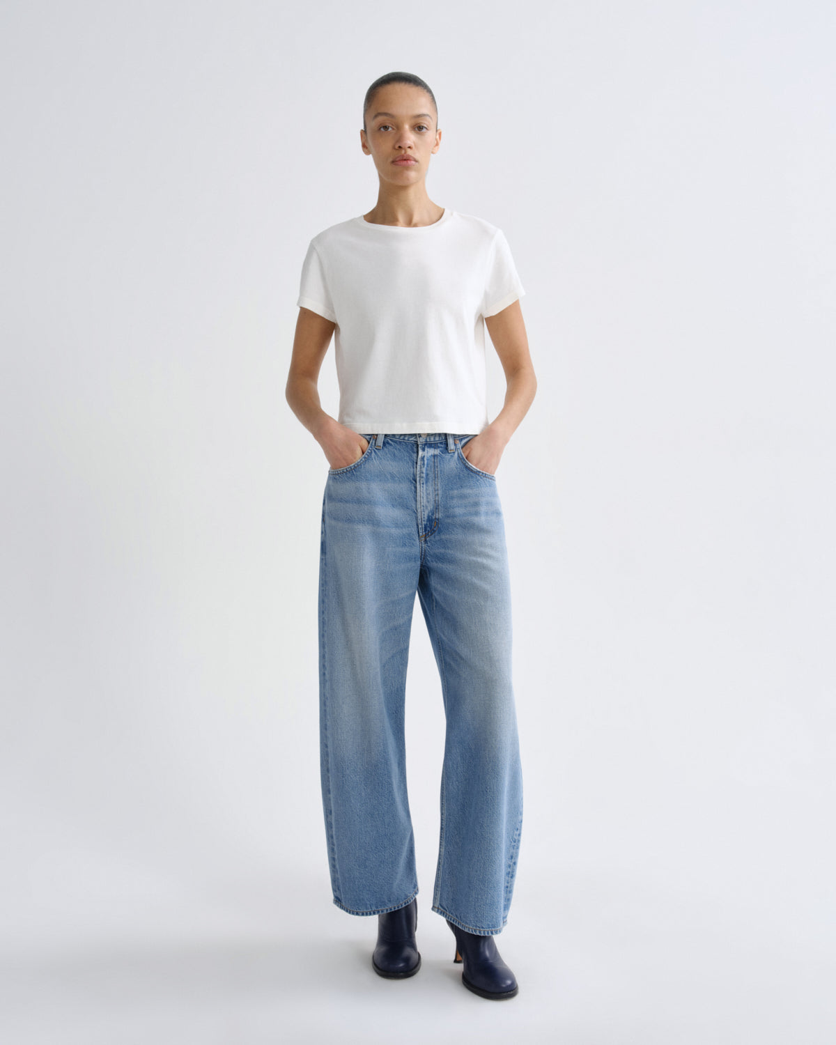 Person wearing a white t-shirt and blue jeans on a white background