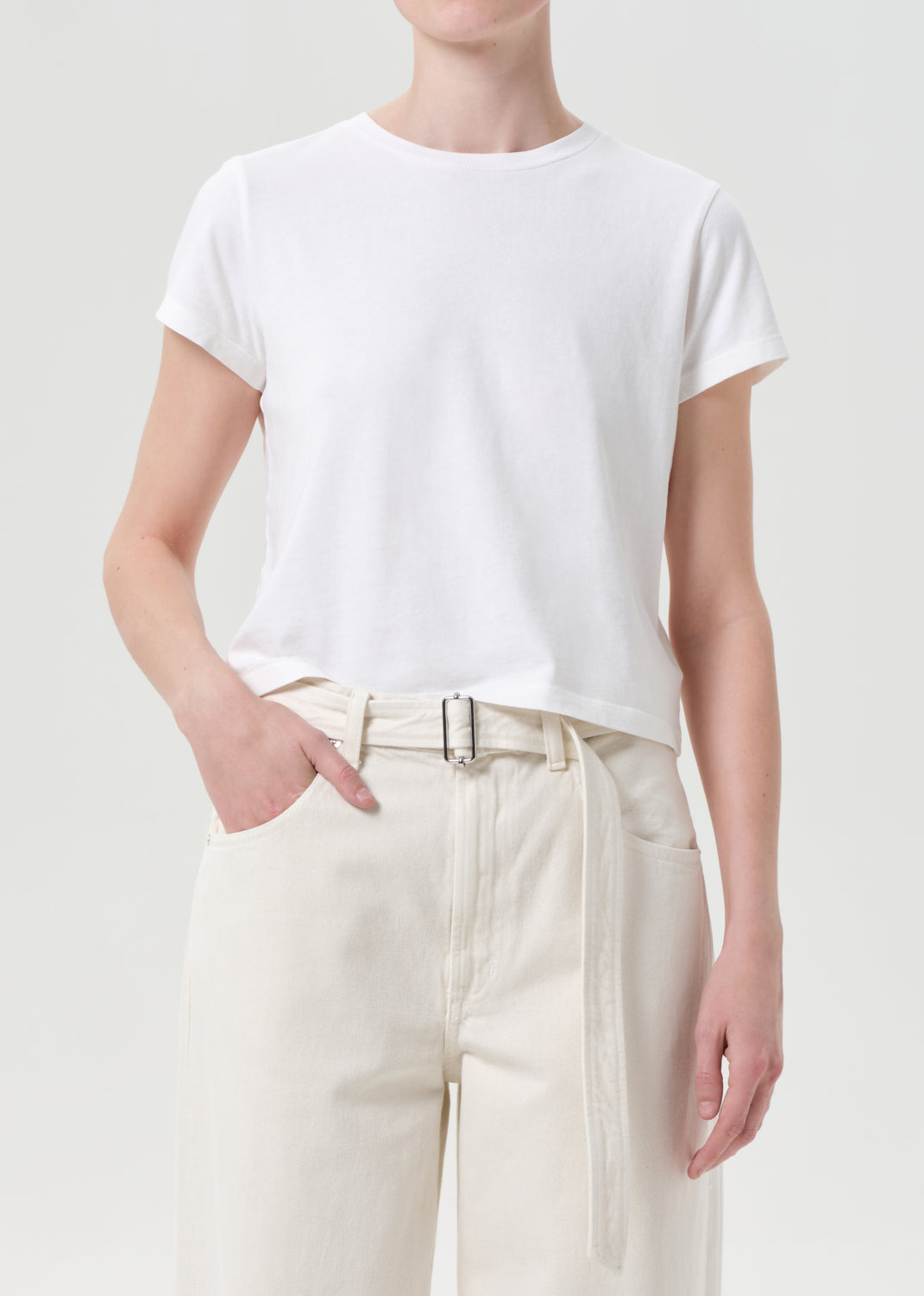 Person wearing a white t-shirt and beige pants on a plain background