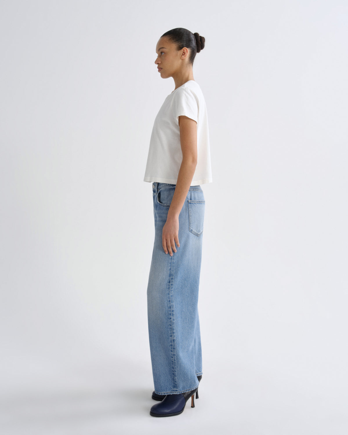 Woman wearing a white t-shirt and light blue jeans on a white background
