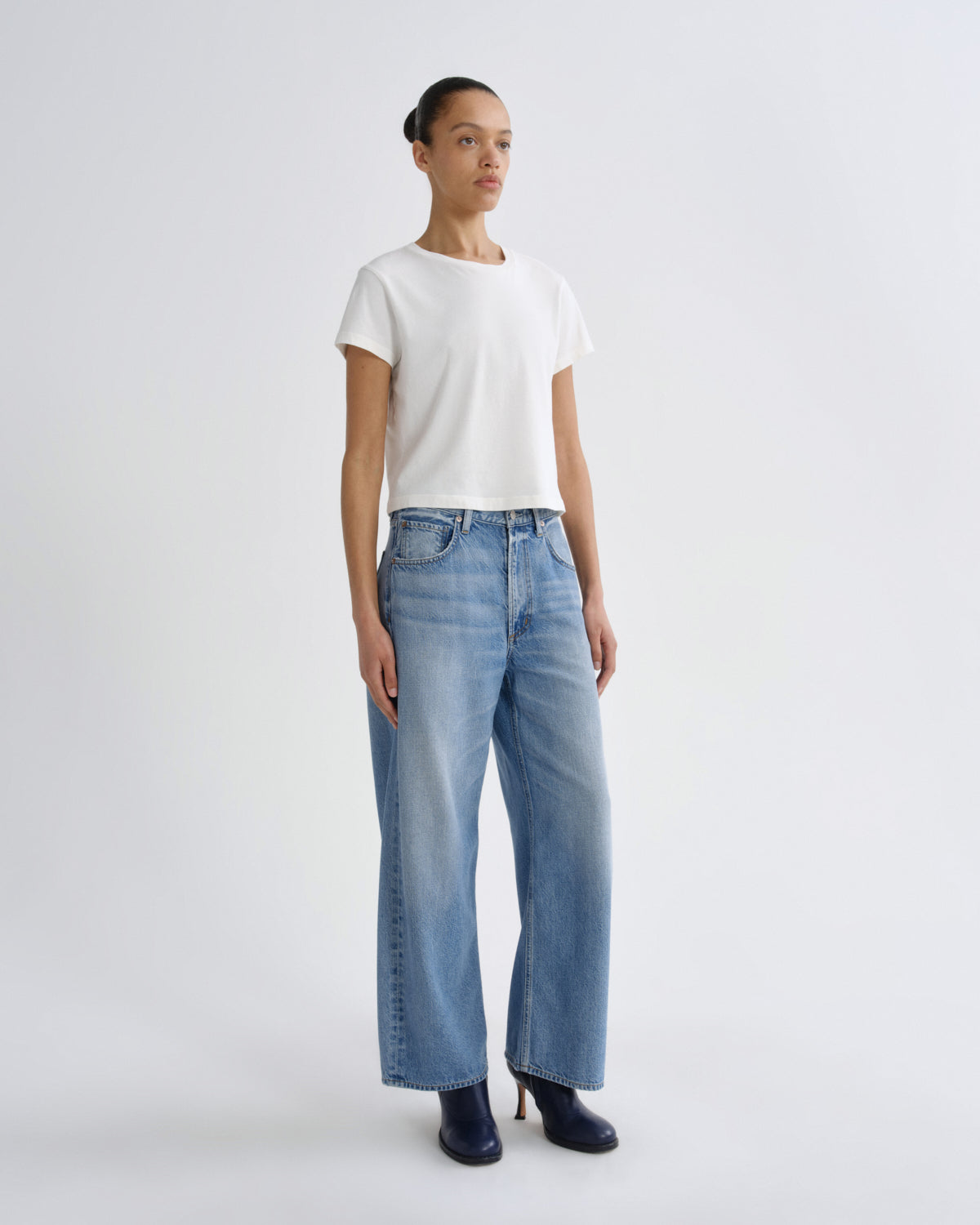 Woman wearing a white t-shirt and blue jeans on a white background