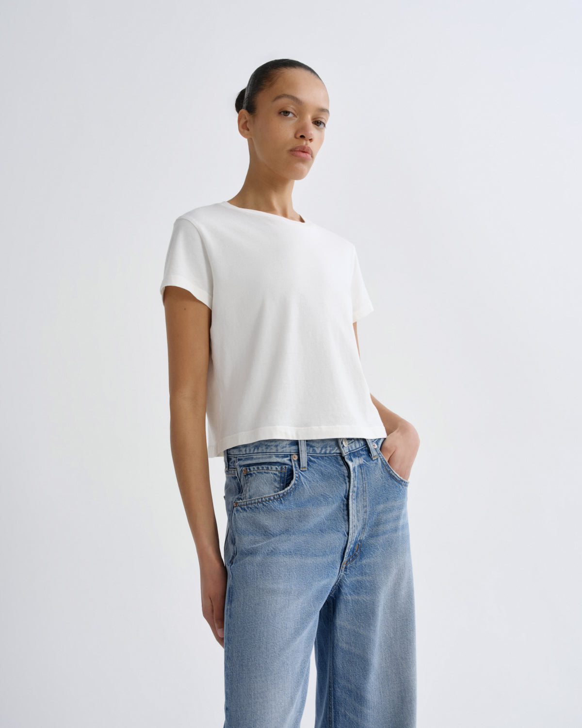 Person wearing a white top and blue jeans on a plain background