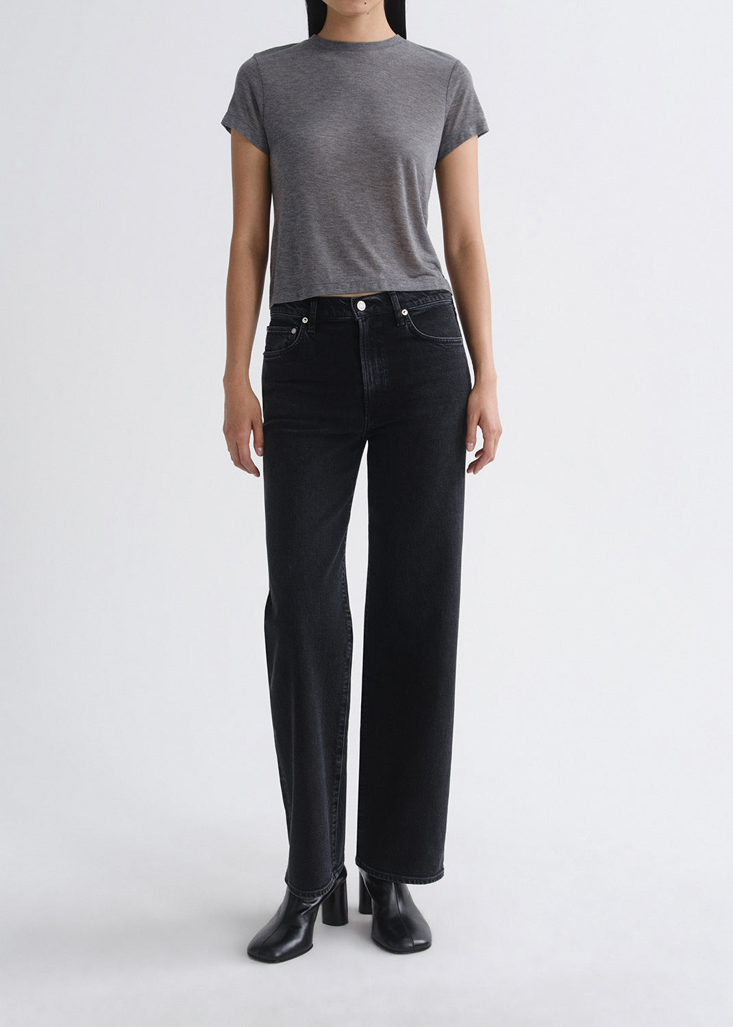 Person wearing a grey t-shirt and black jeans on a grey background