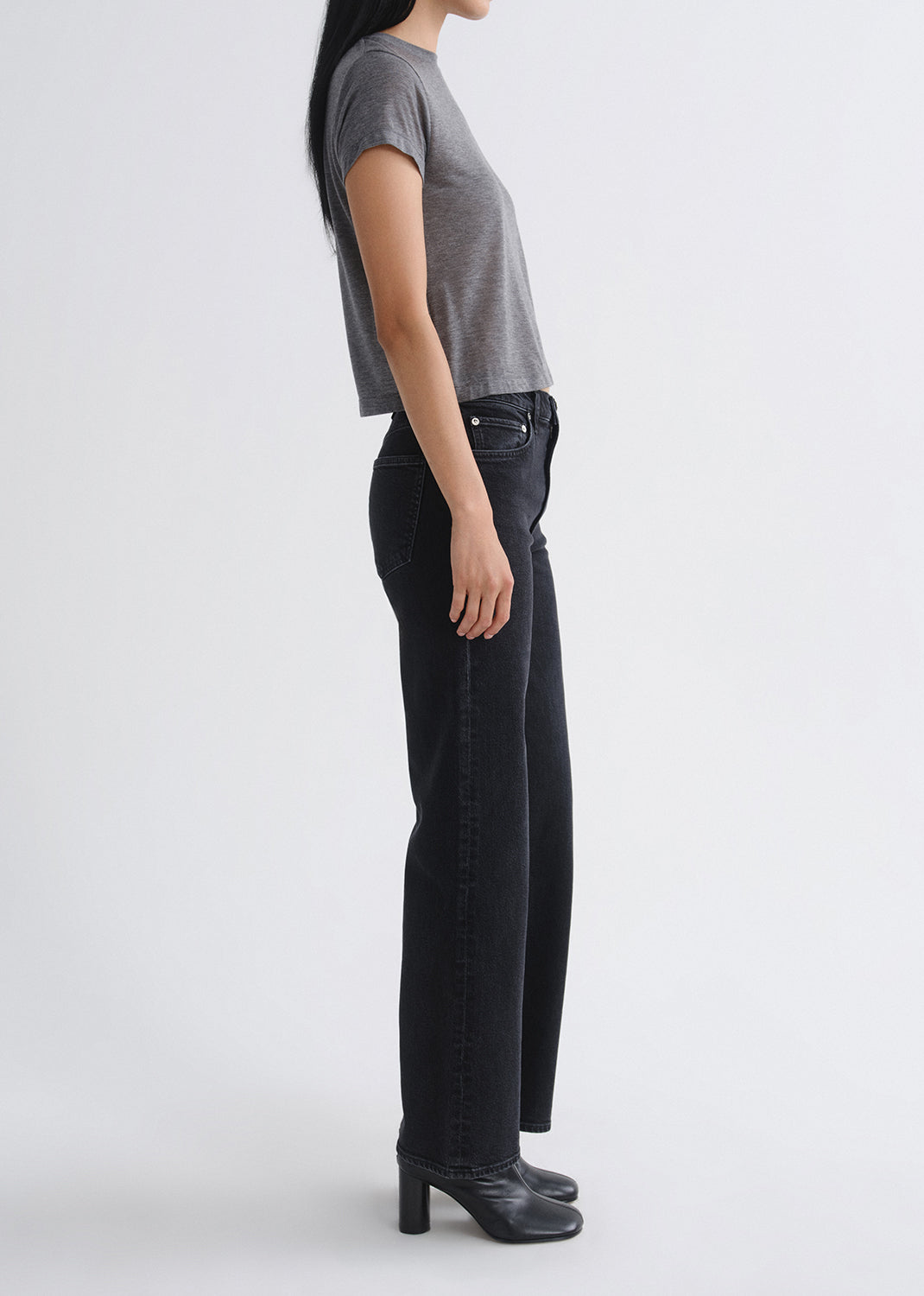Person wearing black jeans and a grey shirt on a grey background