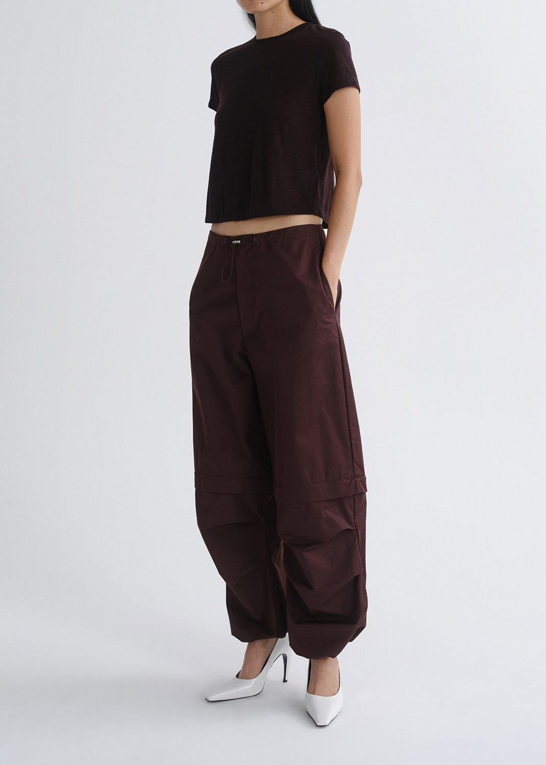 Person wearing a black top and brown wide-leg pants on a grey background