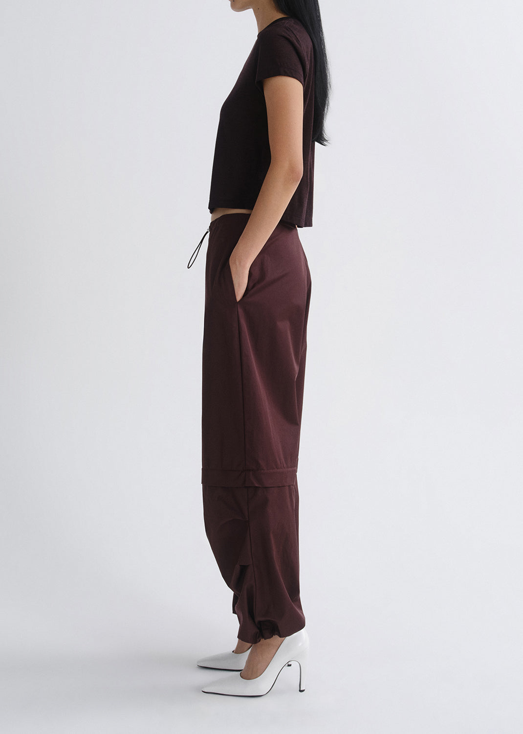 Person wearing a black top and maroon pants on a grey background
