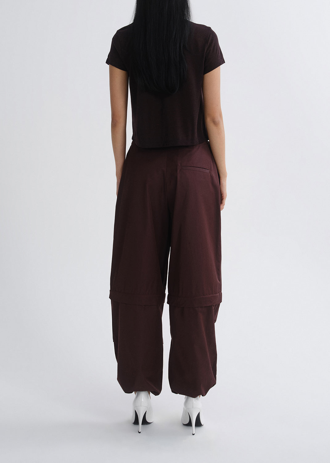 Person wearing a dark brown outfit with wide-leg pants on a grey background
