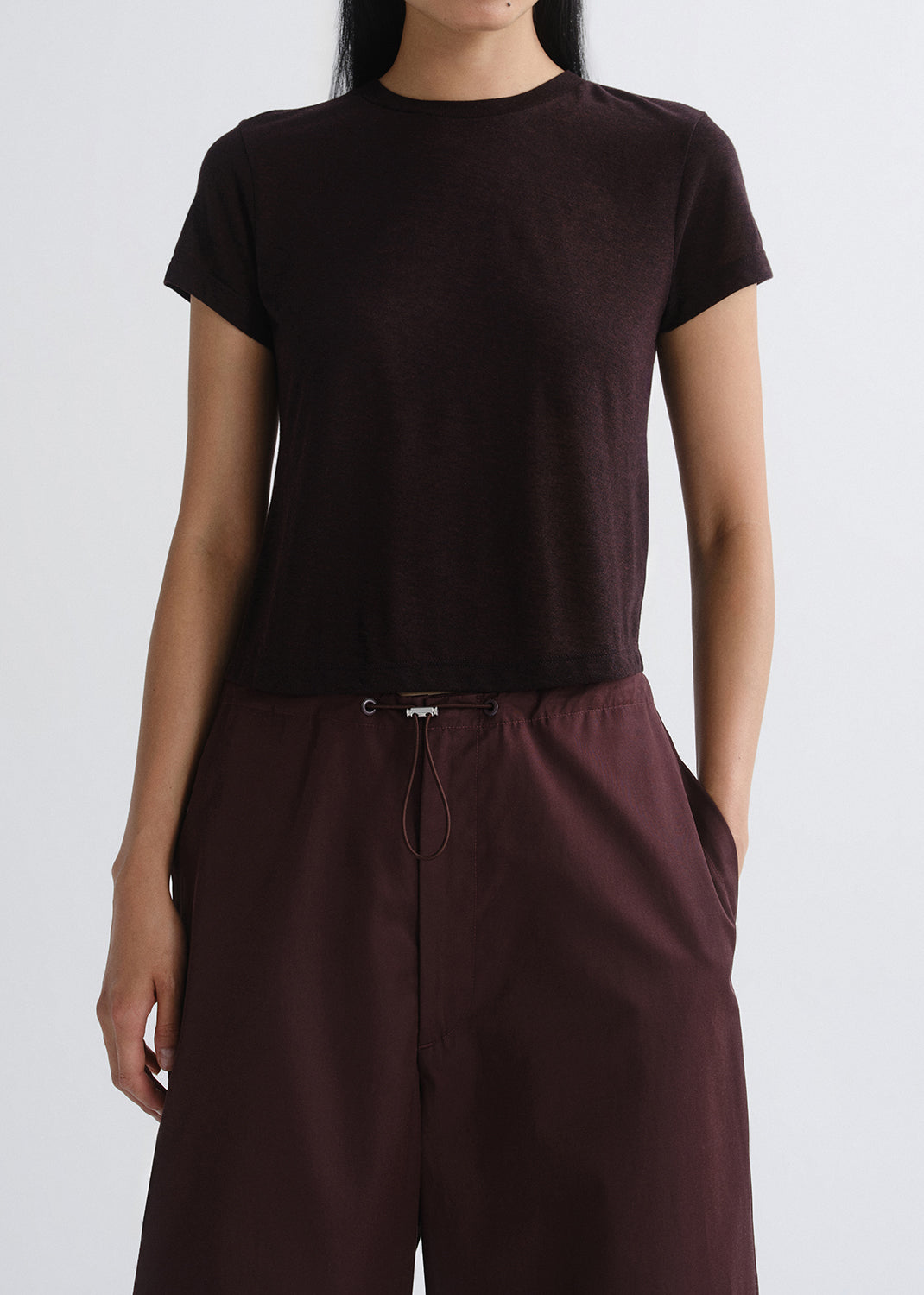 Person wearing a dark brown t-shirt and pants on a grey background