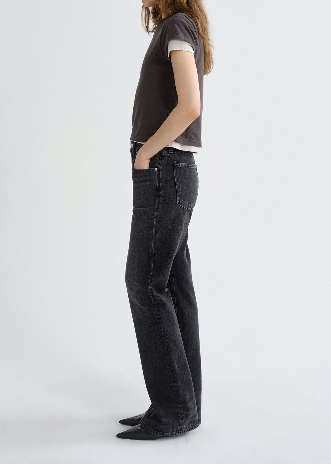 Person wearing black jeans and a dark shirt on a grey background