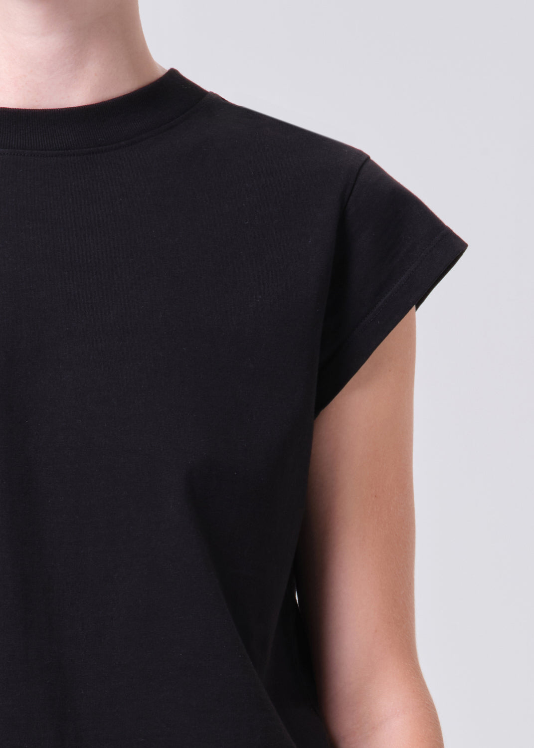 Black sleeveless top worn by a person on a plain background