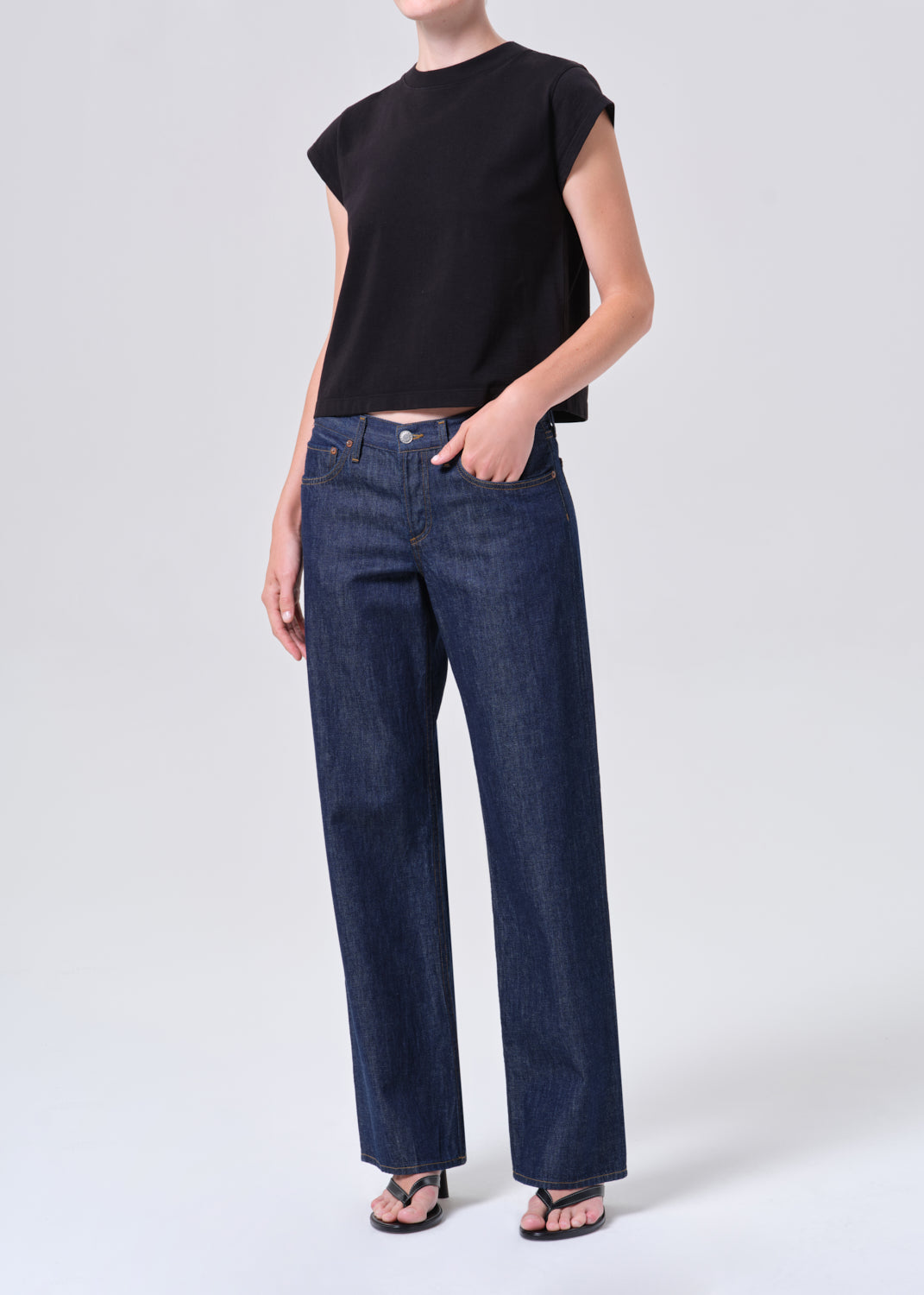 Person wearing a black top and blue jeans on a white background