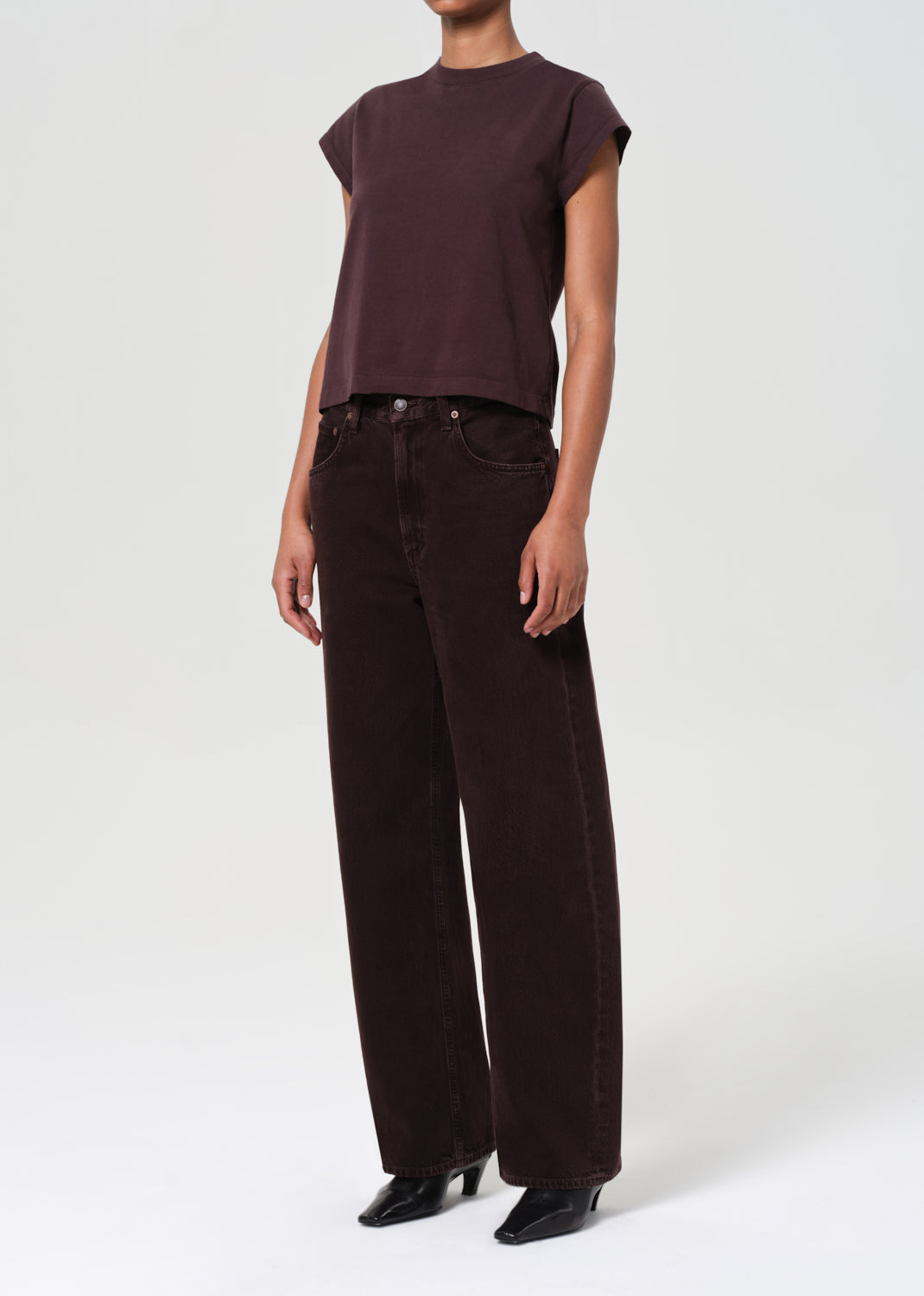 Person wearing a brown top and dark brown wide-leg pants on a white background