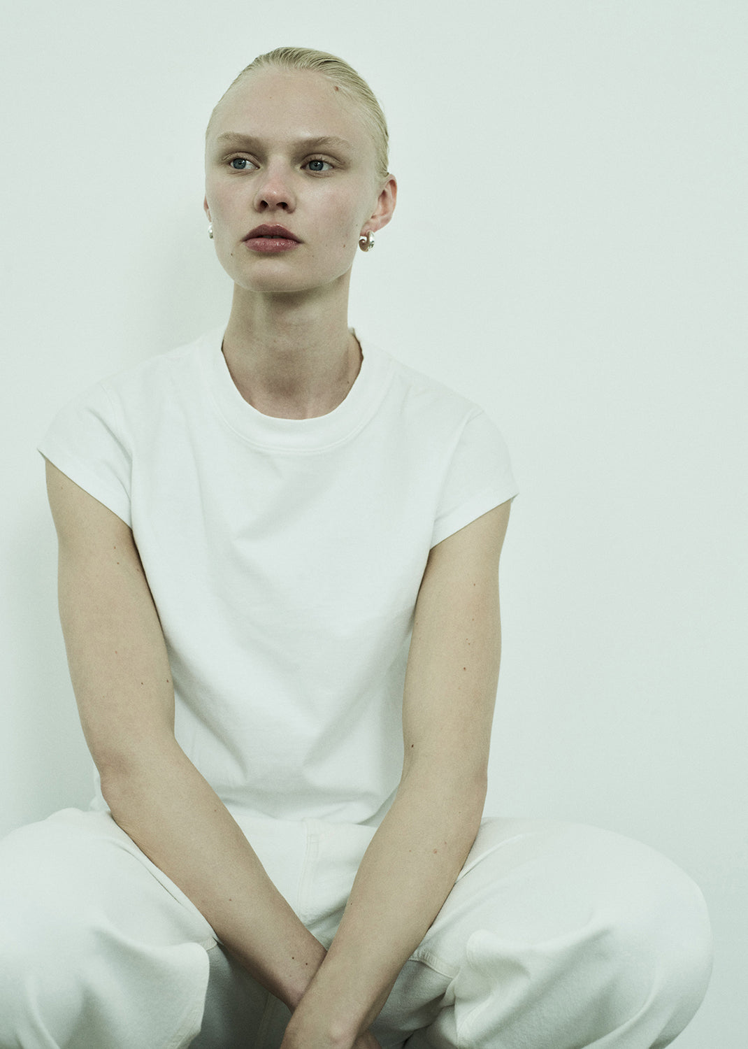 Person wearing a plain white t-shirt and pants against a white background