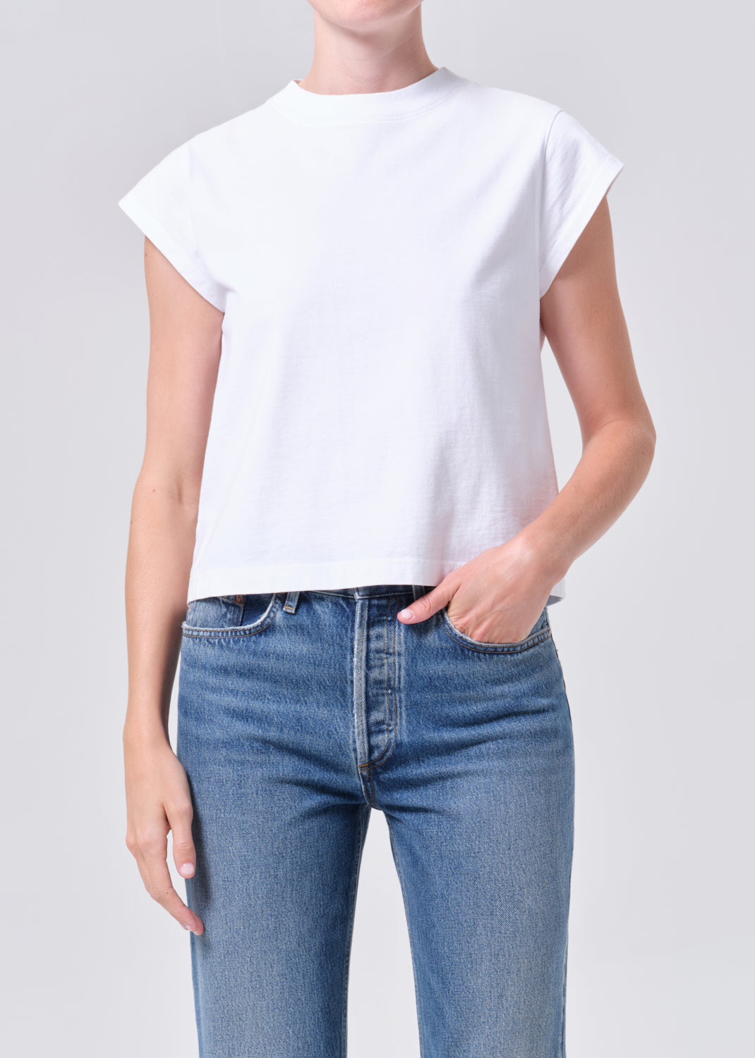 Person wearing a white t-shirt and blue jeans on a plain background