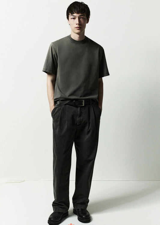 Man wearing a dark green t-shirt and black pants against a white background